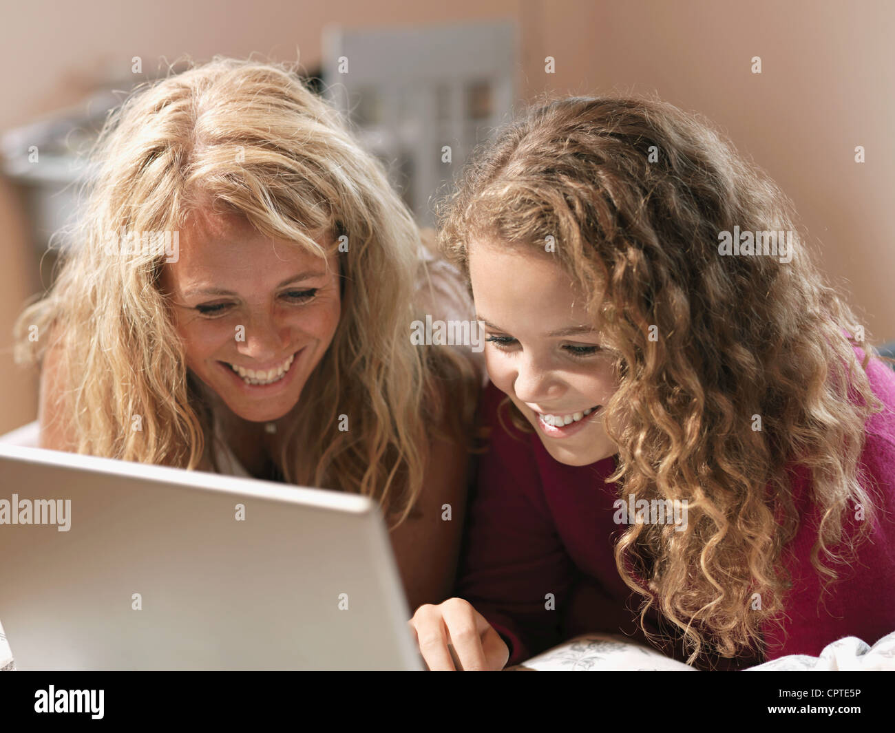 Giovane donna e madre guardando sul computer portatile sul letto Foto Stock