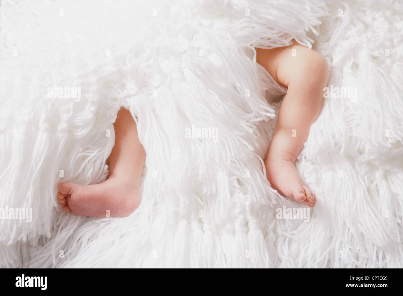 Baby boy per le gambe su coltre bianca Foto Stock