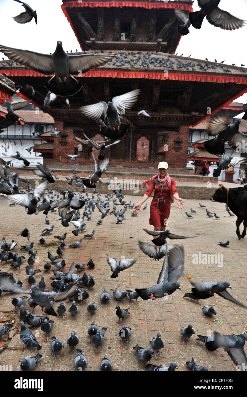 La donna in esecuzione attraverso un gregge di piccioni nella parte anteriore di Jagannath tempio in Durbar Square di Kathmandu, Nepal Foto Stock