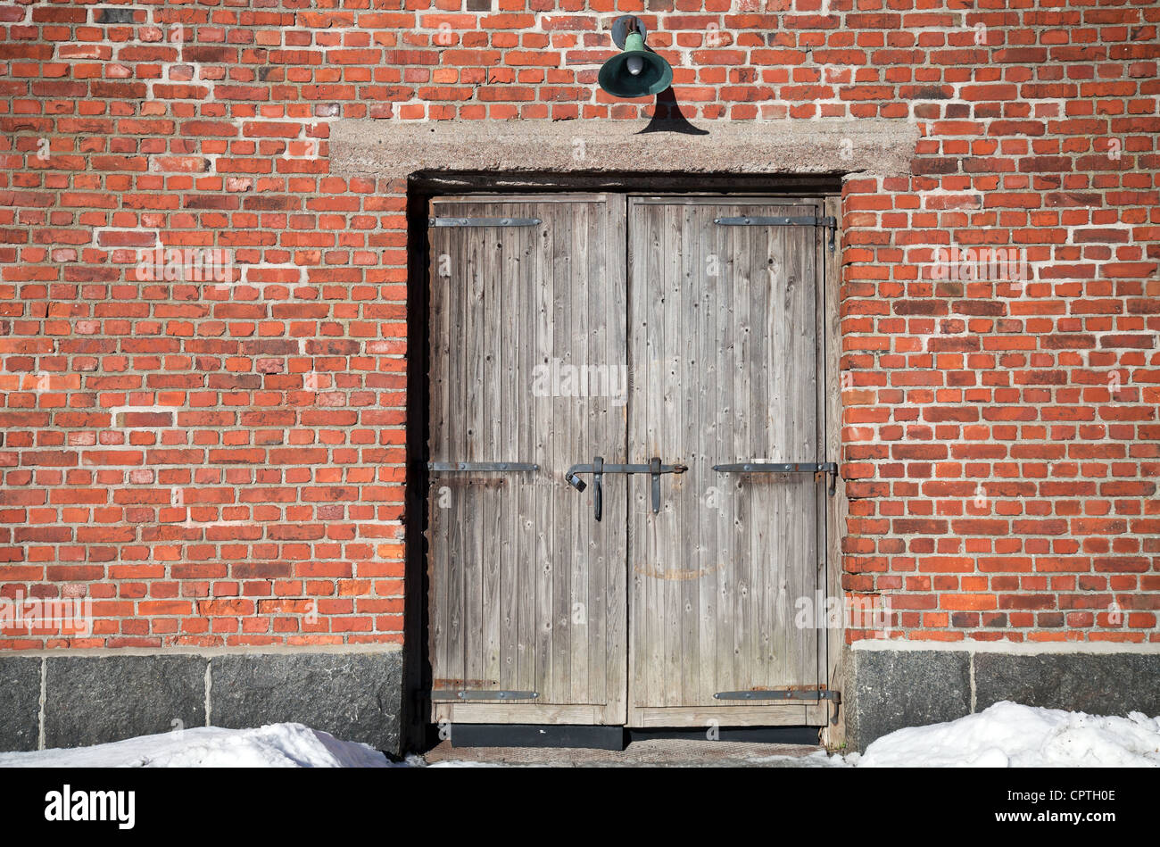 Muro di mattoni di un vecchio edificio con il vecchio weathered cancello in legno Foto Stock