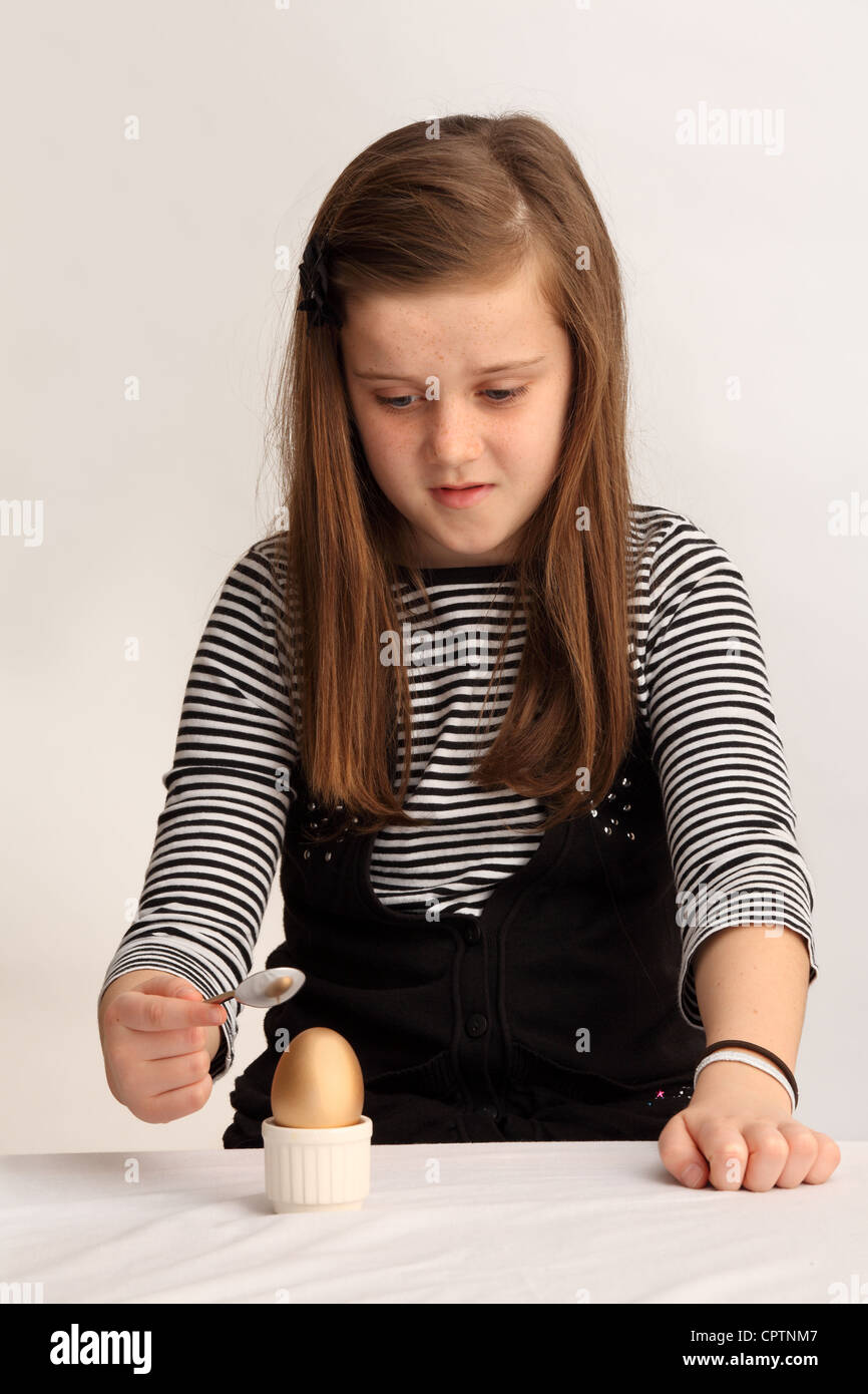 Immagine concettuale di una bambina di nove anni che sta per aprire un uovo d'oro. Foto Stock