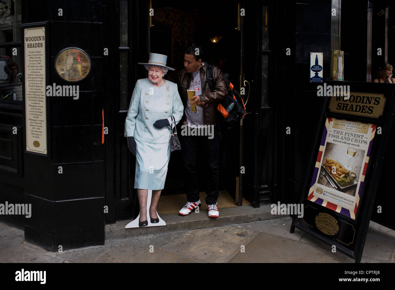 I londinesi in strada con una vita di cartone di dimensioni ritaglio della regina Elisabetta sorge all'entrata di un pub nella città di Londra in vista di un fine settimana di celebrazioni a livello nazionale per il monarca del Giubileo di diamante. Foto Stock