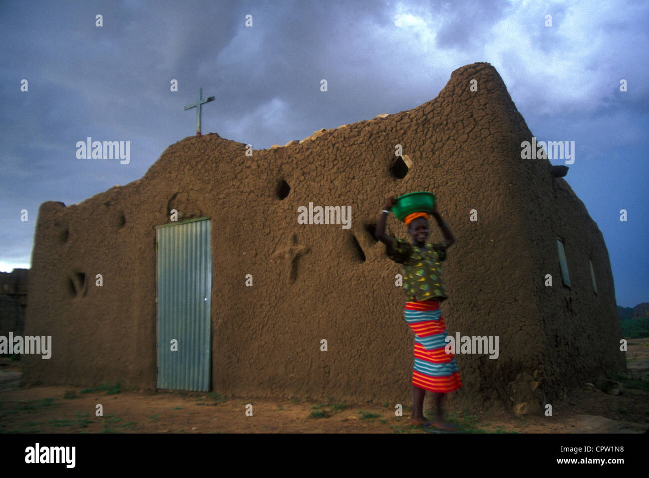 Donna africana passando un fango chiesa costruita nel Paese Dogon del Mali, Africa occidentale Foto Stock