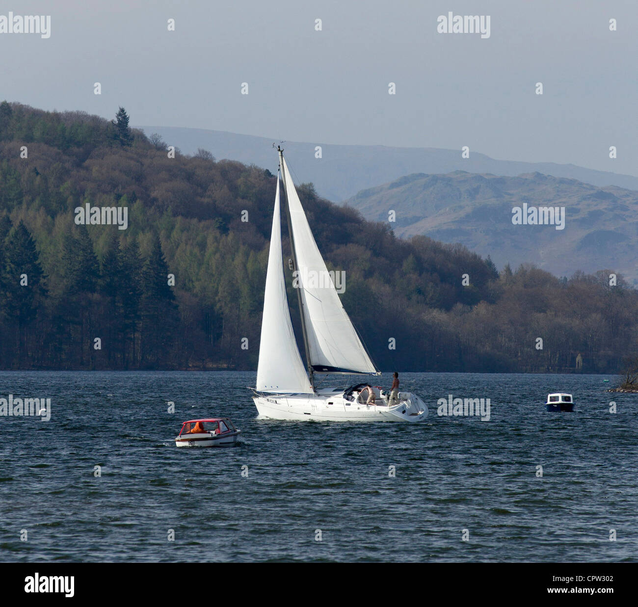 Yacht a pieno la vela in inverno sul lago di Windermere con le montagne e brughiere in background Foto Stock