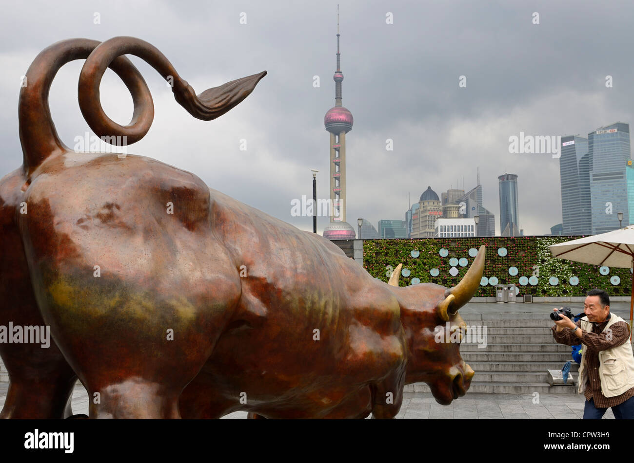 Turistica prendendo foto del Bund bull con lo skyline di Shanghai torri finanziari Repubblica Popolare Cinese Foto Stock