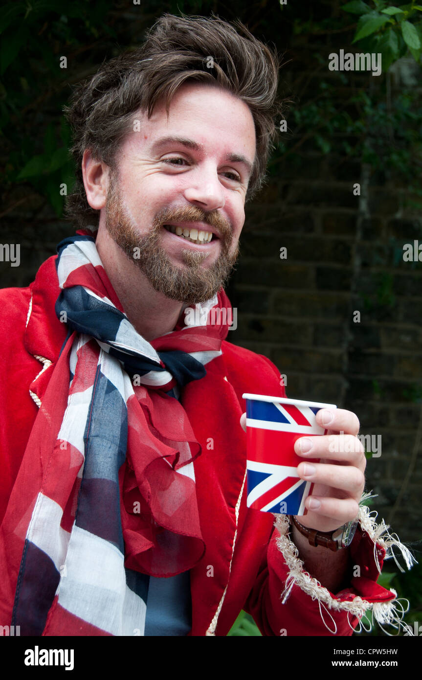Queen's Jubillegal flottiglia parte flottante. L'uomo indossando giacca rossa , rosso bianco e blu sciarpa con Unione Jack bicchiere di carta Foto Stock