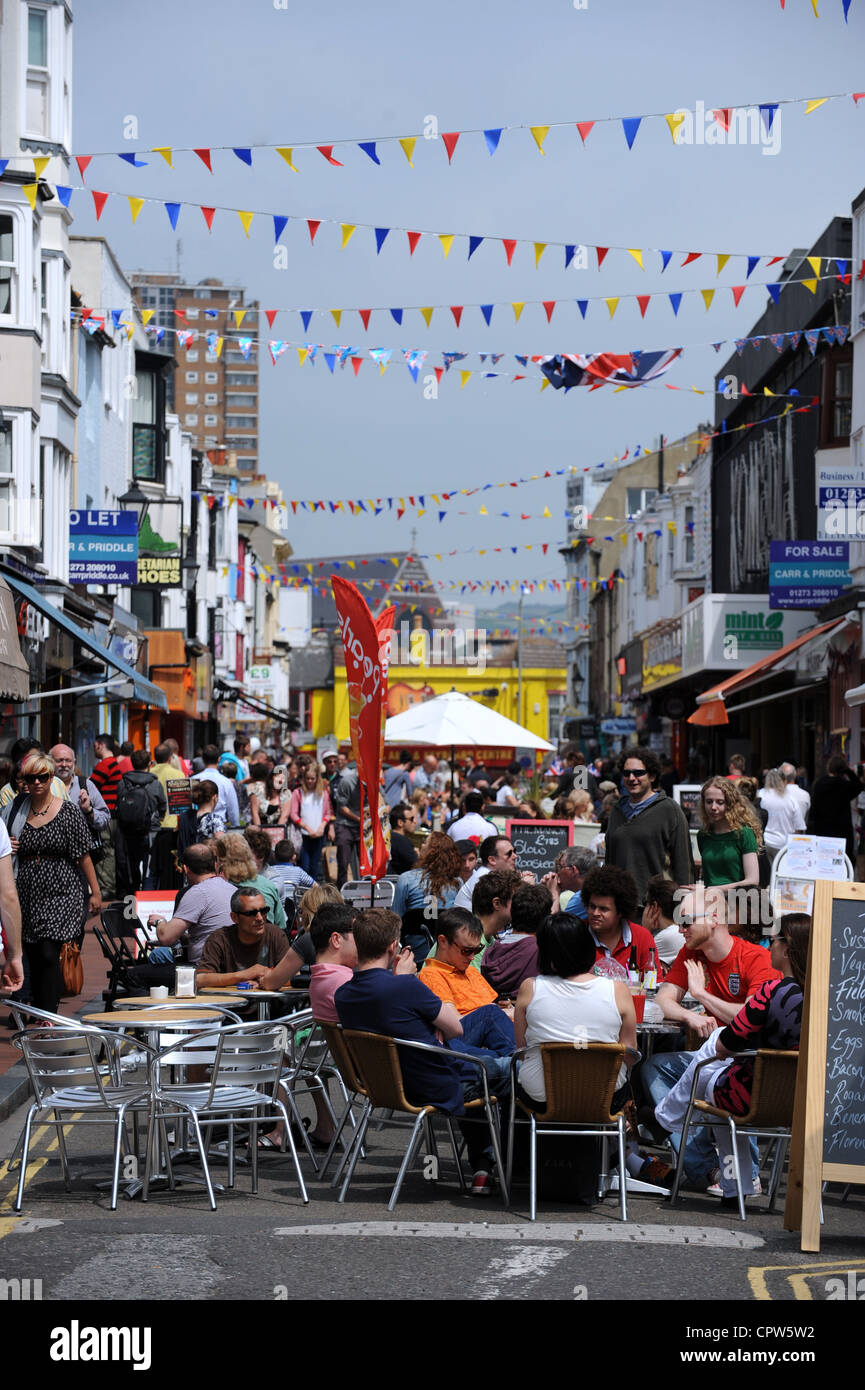 Strada trafficata in Nord Laines area di Brighton con persone sedute al tavolo e sedie in bar e caffetterie Sussex Regno Unito 2012 Foto Stock