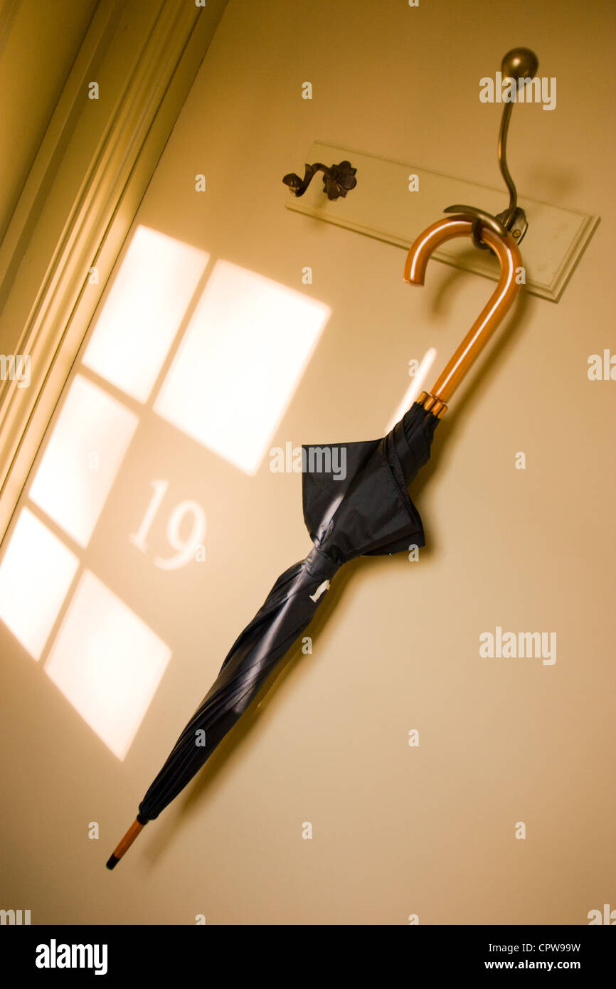 Un ombrello appeso accanto all'ombra proiettata del numero 19 da una finestra nelle vicinanze Foto Stock