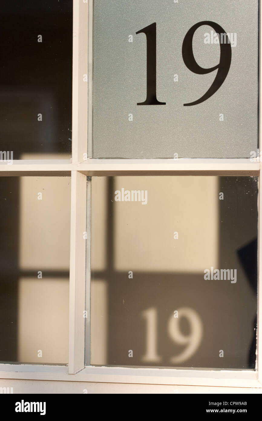 Il numero 19 attaccato in una finestra la colata è ombra dietro Foto Stock