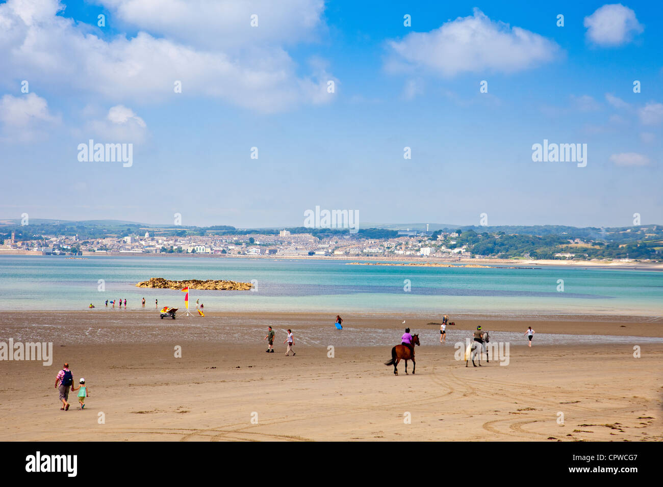 I piloti a cavallo sulla spiaggia di Mount's Bay a Marazion Cornwall Inghilterra Regno Unito con la città di Penzance oltre Foto Stock