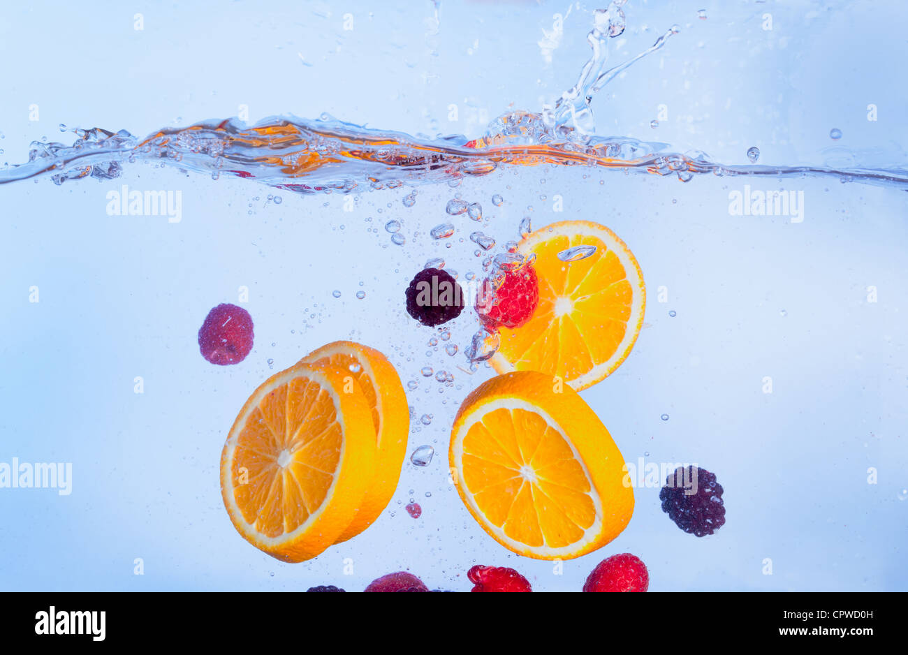 Frutta fresca cade sotto l'acqua con una Splash, sfondo blu Foto Stock