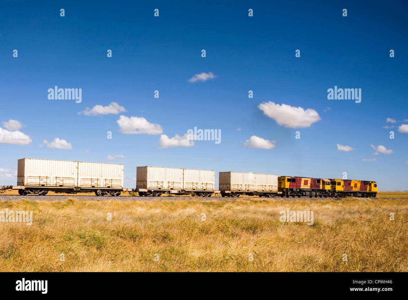 Treno Diesel tirando i contenitori di spedizione attraverso zone rurali del Queensland praterie naturali Foto Stock