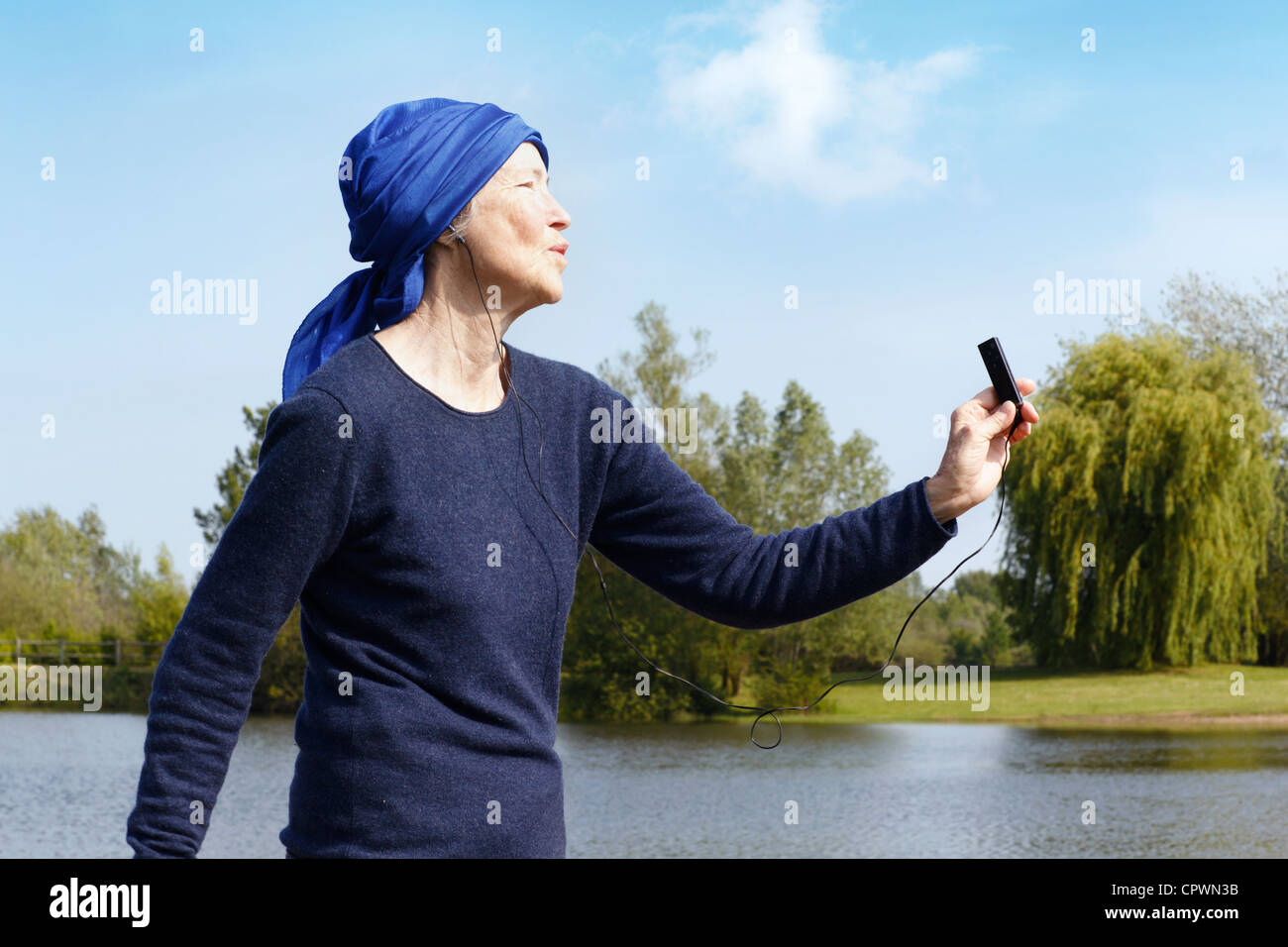 Senior donna con lettore mp3 dal lago, vista laterale. Foto Stock