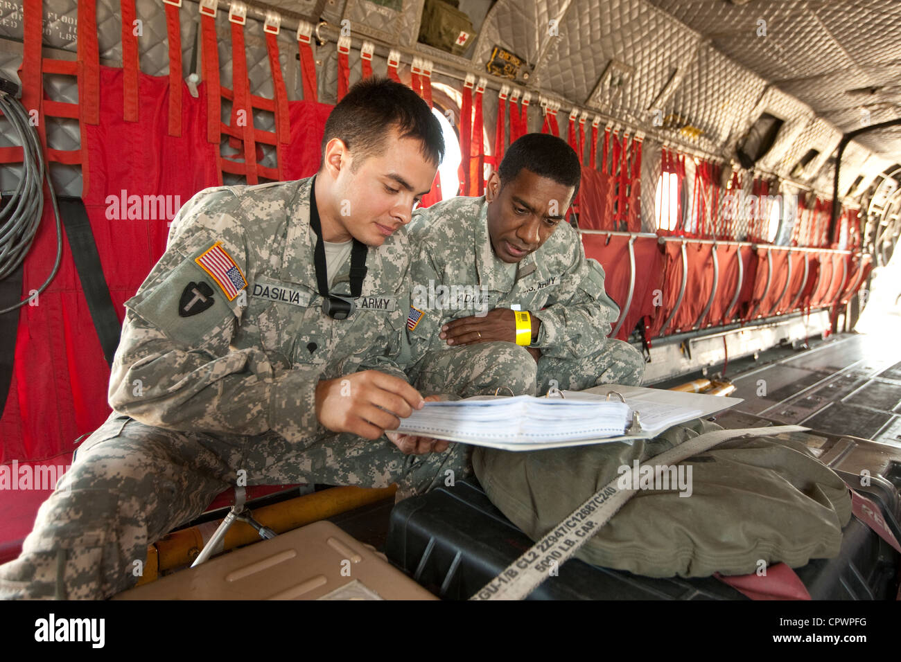 I membri dell'esercito degli Stati Uniti in uniforme di riesaminare le informazioni all'interno di un aereo militare di emergenza per i soccorsi in caso di calamità CH47 Foto Stock