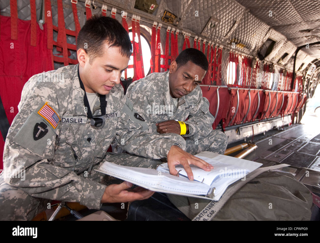 I membri dell'esercito degli Stati Uniti in uniforme di riesaminare le informazioni all'interno di un aereo militare di emergenza per i soccorsi in caso di calamità CH47 Foto Stock