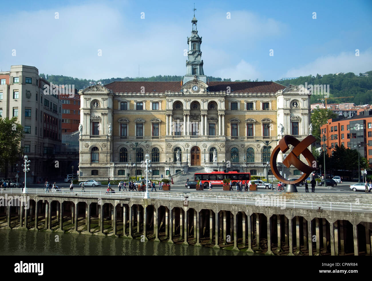 Bilbao's grand Town Hall, con palificazioni lungo il fiume Bilbao in primo piano, vista attraverso il fiume Foto Stock