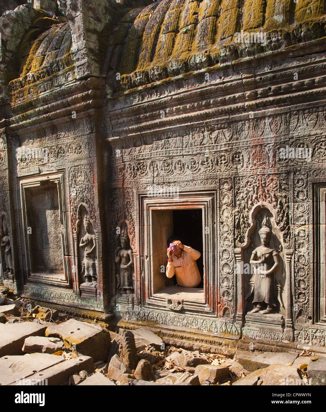 Una guida turistica ceppi al telaio una fotografia dal di dentro le rovine, Ta Prohm, Angkor, Siem Reap Provincia, Cambogia, Foto Stock