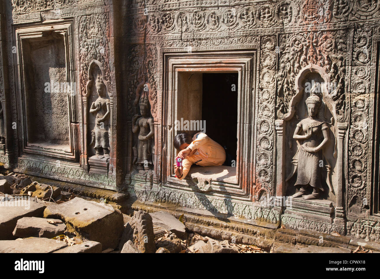 Una guida turistica ceppi al telaio una fotografia dal di dentro le rovine, Ta Prohm, Angkor, Siem Reap Provincia, Cambogia, Foto Stock