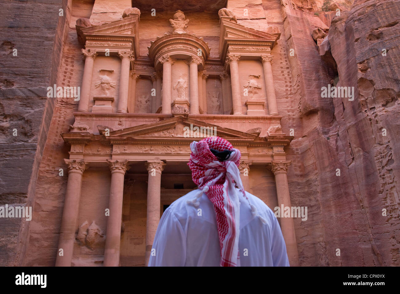 Uomo arabo guardando la facciata del Tesoro (Al Khazneh), Petra, Giordania (Patrimonio Mondiale dell'UNESCO) Foto Stock