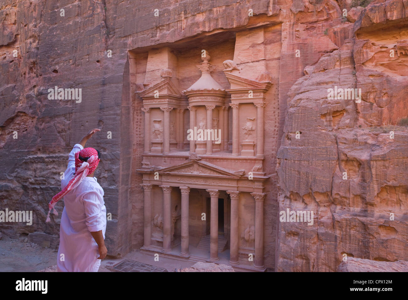 Uomo arabo guardando la facciata del Tesoro (Al Khazneh), Petra, Giordania (Patrimonio Mondiale dell'UNESCO) Foto Stock