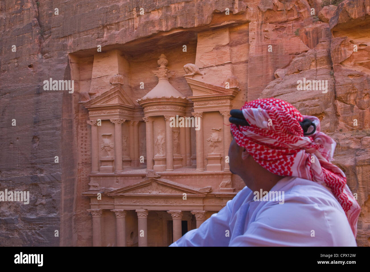 Uomo arabo guardando la facciata del Tesoro (Al Khazneh), Petra, Giordania (Patrimonio Mondiale dell'UNESCO) Foto Stock
