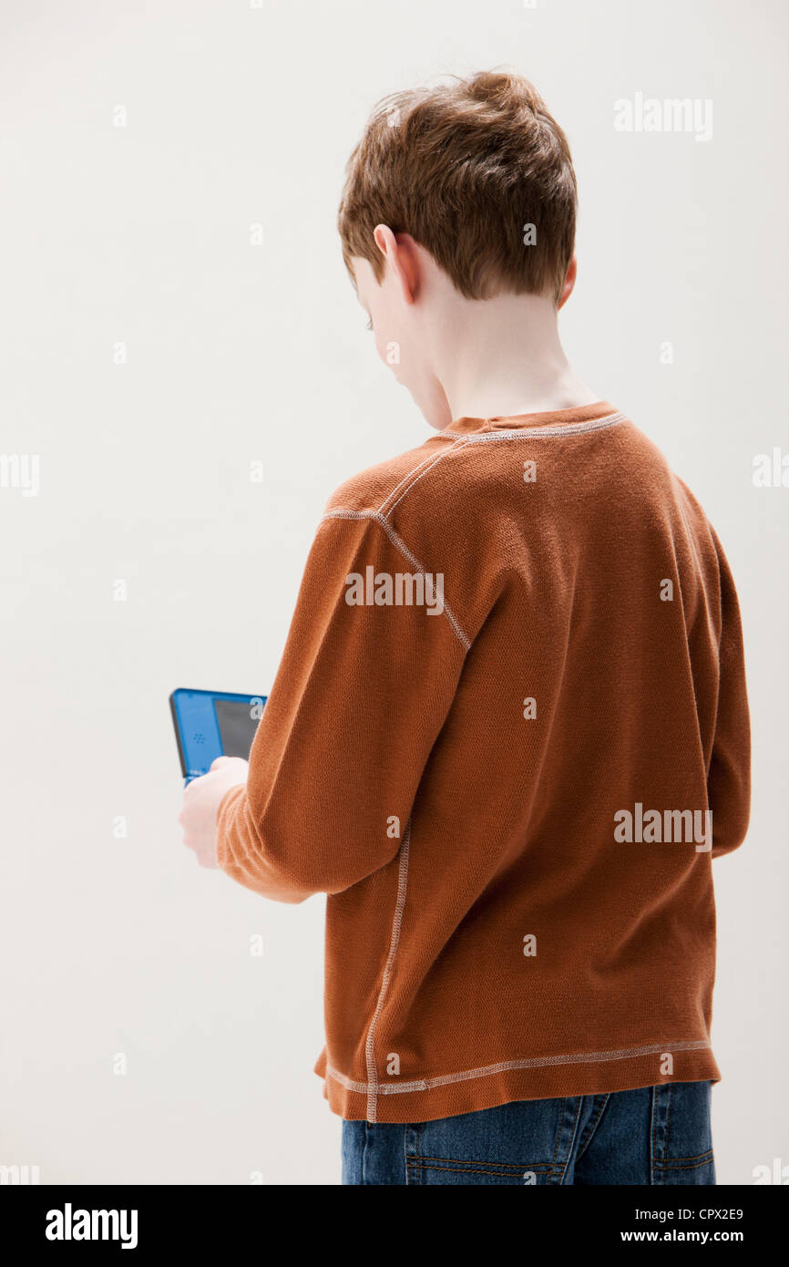 Ragazzo in marrone maglione giocando a mano video gioco, studio shot Foto Stock