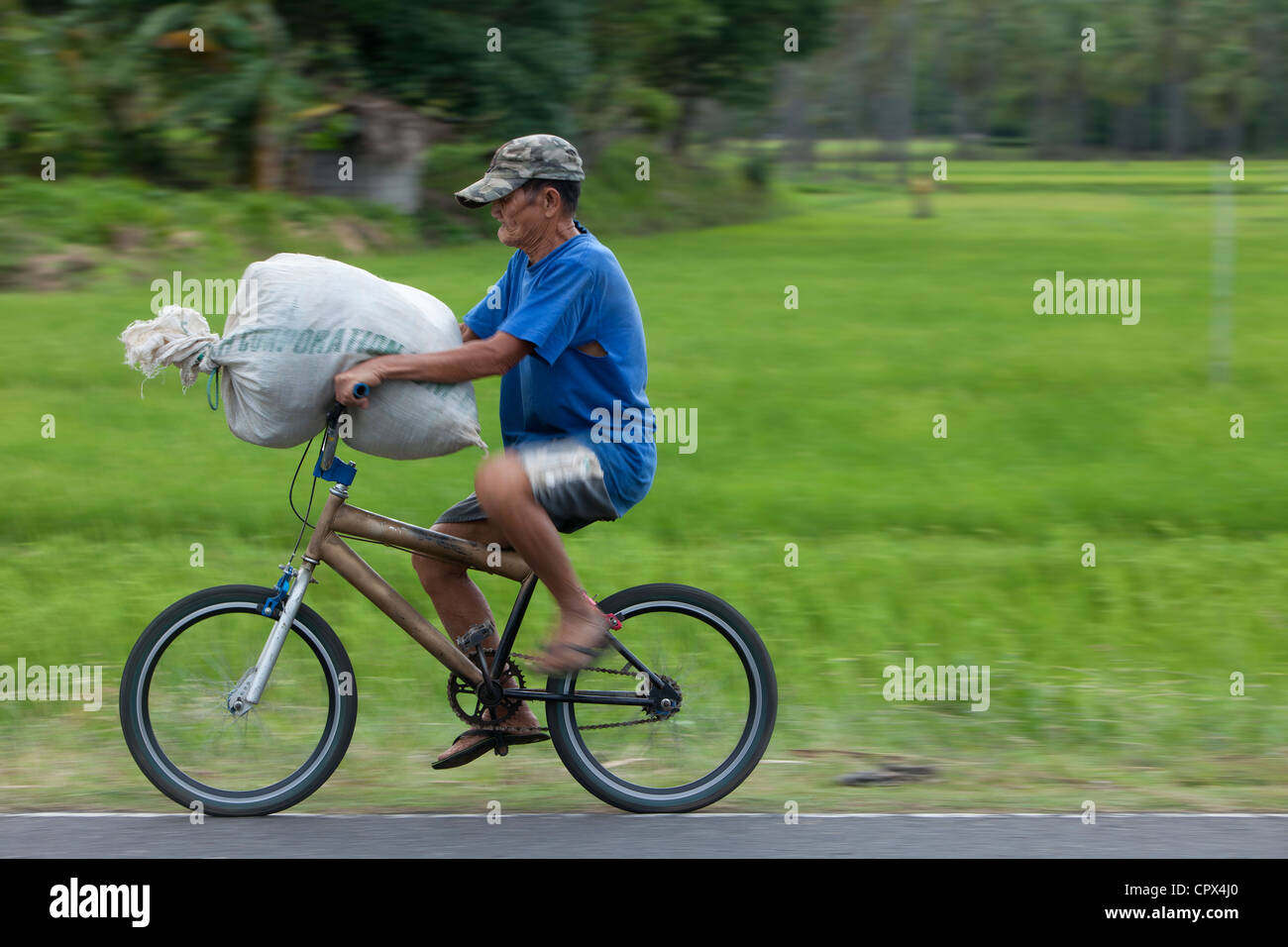 Un uomo che porta un sacco di riso su una bici, Negros, Filippine Foto Stock