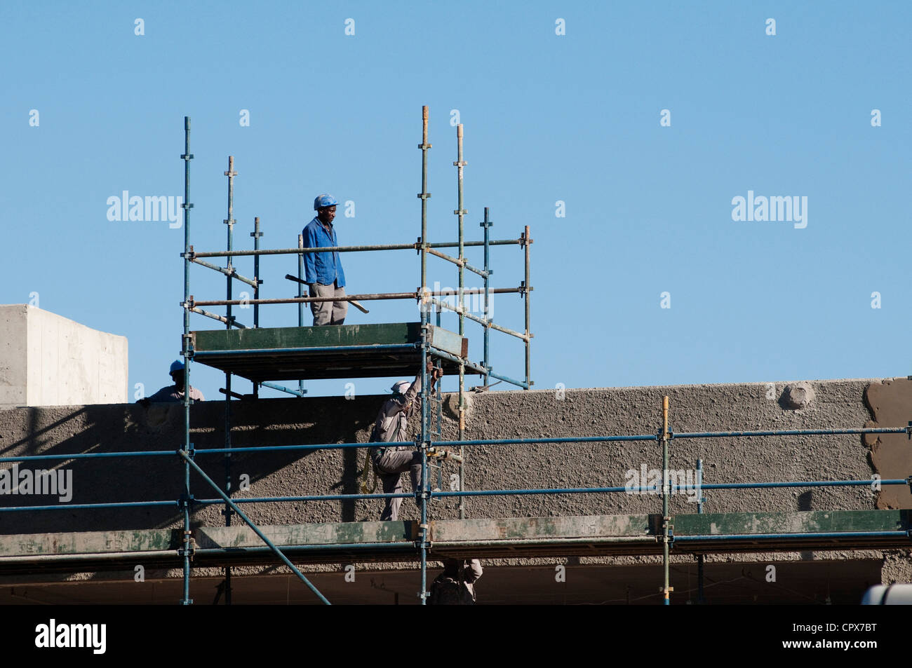 Operaio edile permanente sulla sommità del ponteggio Foto Stock