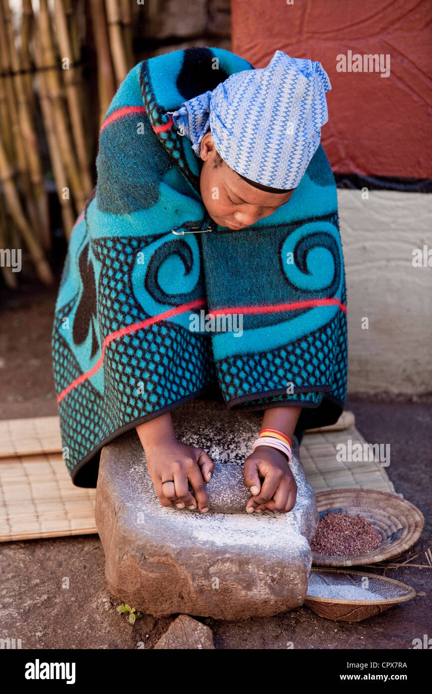 Un tradizionale donna africana macina grano su una roccia Foto Stock