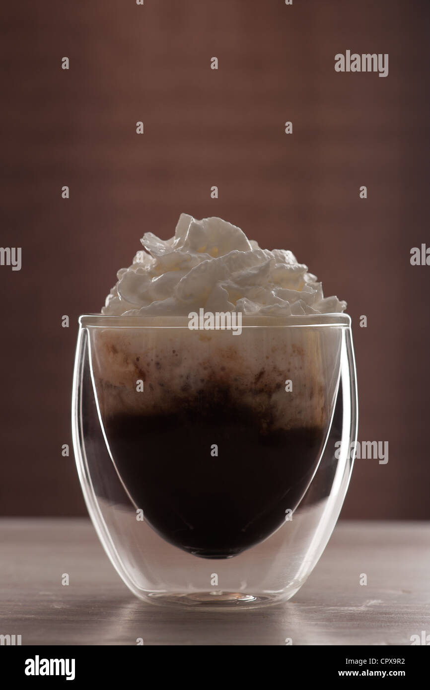 Un vetro trasparente di cioccolata calda coperta con panna montata. Foto Stock