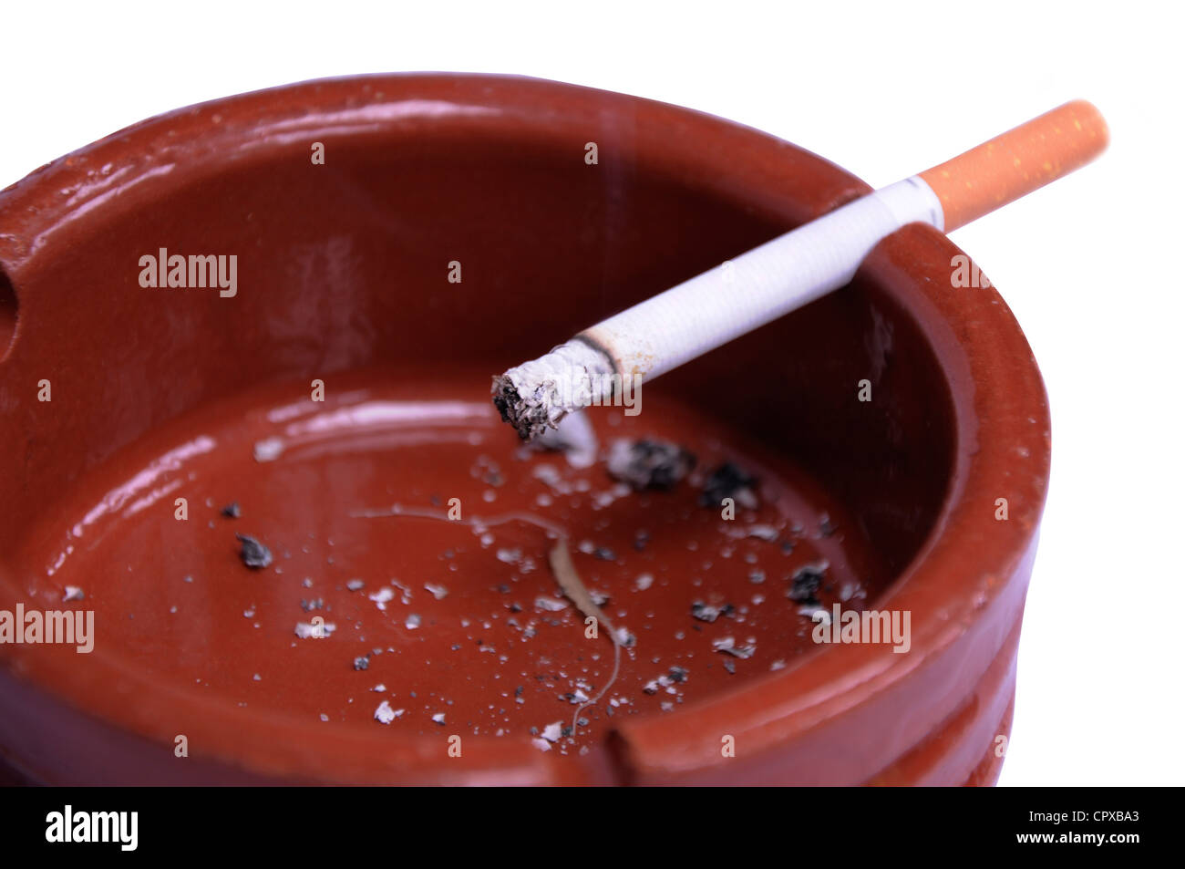 Un parzialmente fumato sigarette in un colore borgogna posacenere con cenere nel vassoio Foto Stock