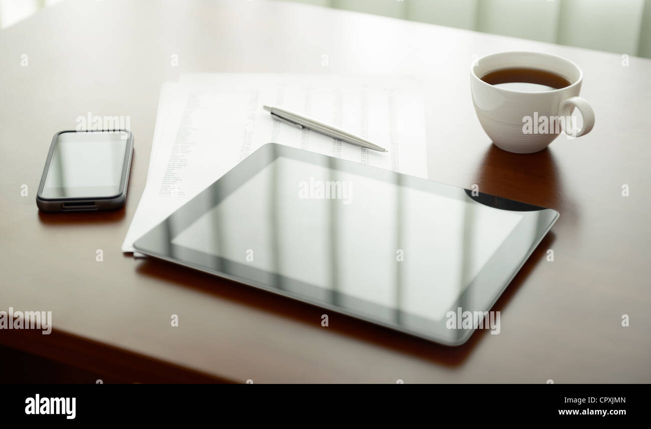Ambiente di lavoro moderno con tavoletta digitale e telefono cellulare, una tazza di tè, penna e carta con i numeri. Foto Stock