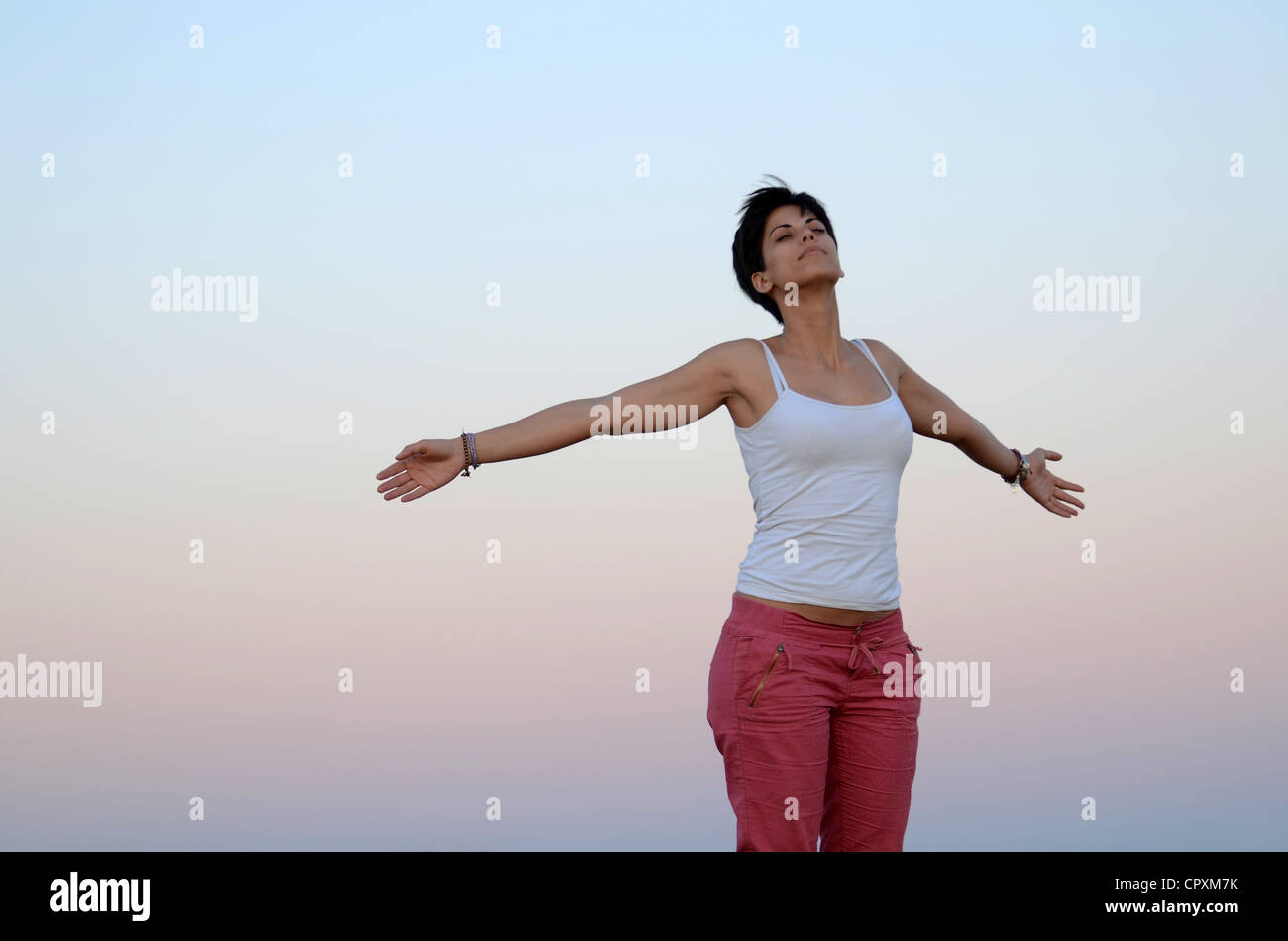 Attraente giovane donna si rilassa in natura con braccia aperte Foto Stock