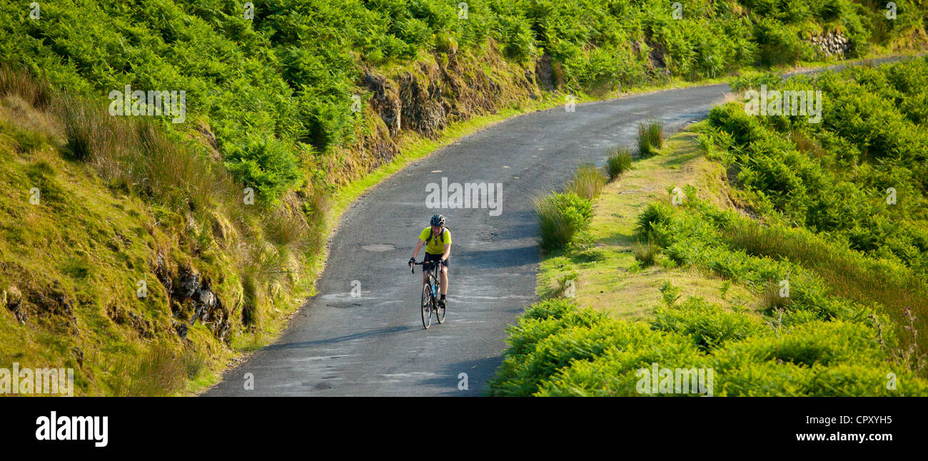 Cicloturismo lungo la strada di campagna attraverso monti Pennini in Lake District National Park, Regno Unito Foto Stock