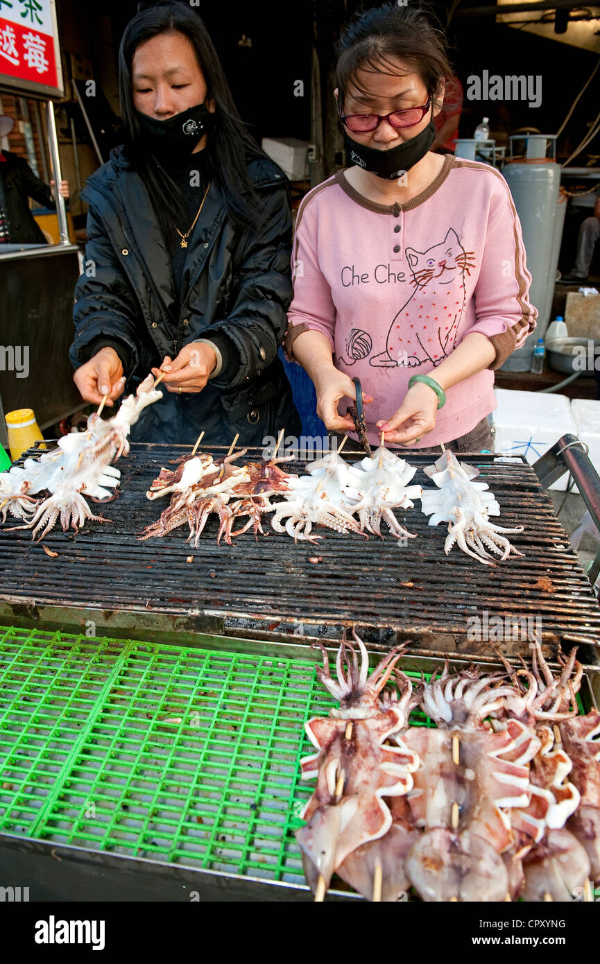 Taiwan, Kaohsiung, l'Isola di Cijin, mercato di pesce, calamari alla griglia si erge Foto Stock