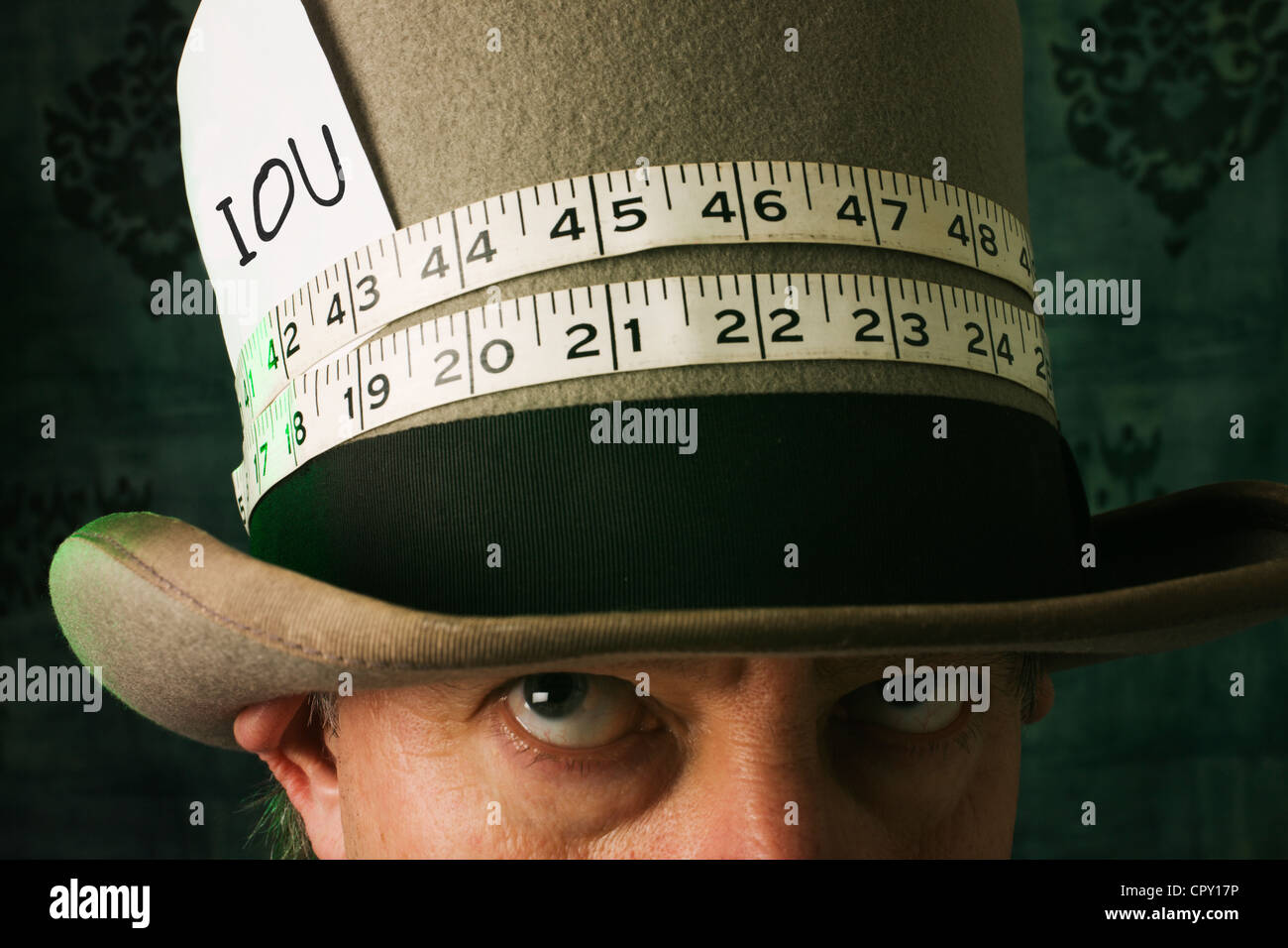 Un Mad Hatter come uomo guardando le IOU sul suo cappello. Foto Stock
