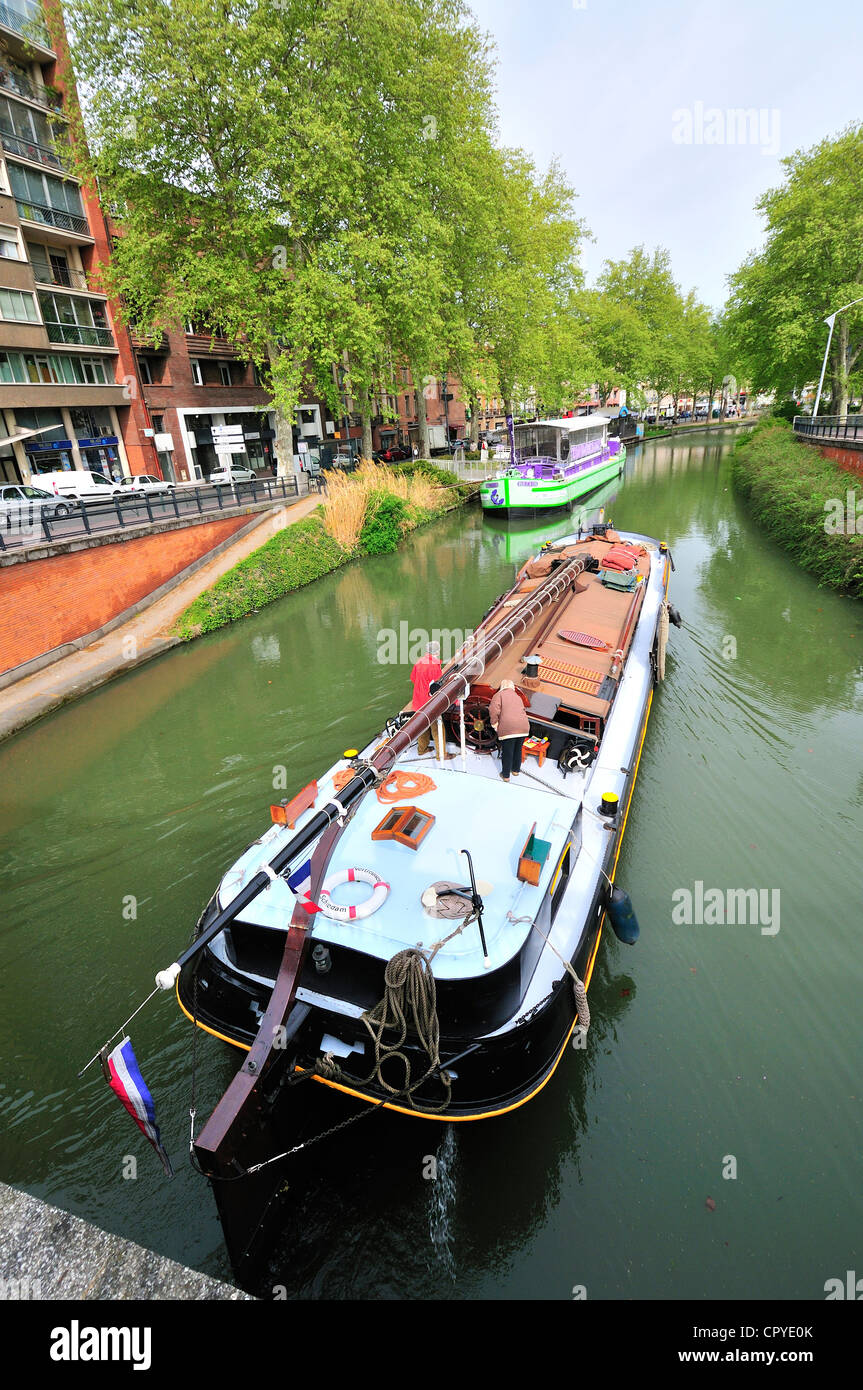 Dutch Barge passando sotto il ponte vicino Toulouse Gare Matabiau lungo il Canal du Midi con la Maison de la Violette chiatta dietro, Francia Foto Stock