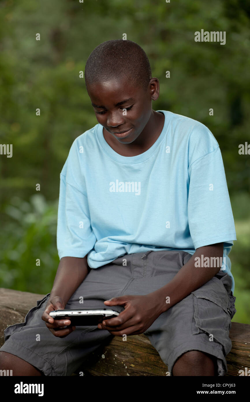 Bambino africano giocando con una console di gioco al di fuori Foto Stock