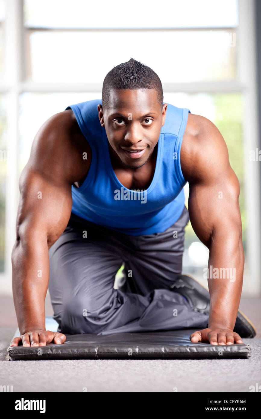 Muscolare giovane maschio nero pone in una palestra Foto Stock