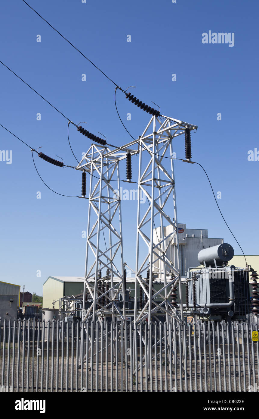 Tralicci elettrici ed edifici industriali fabbriche contro un cielo blu senza nuvole Foto Stock