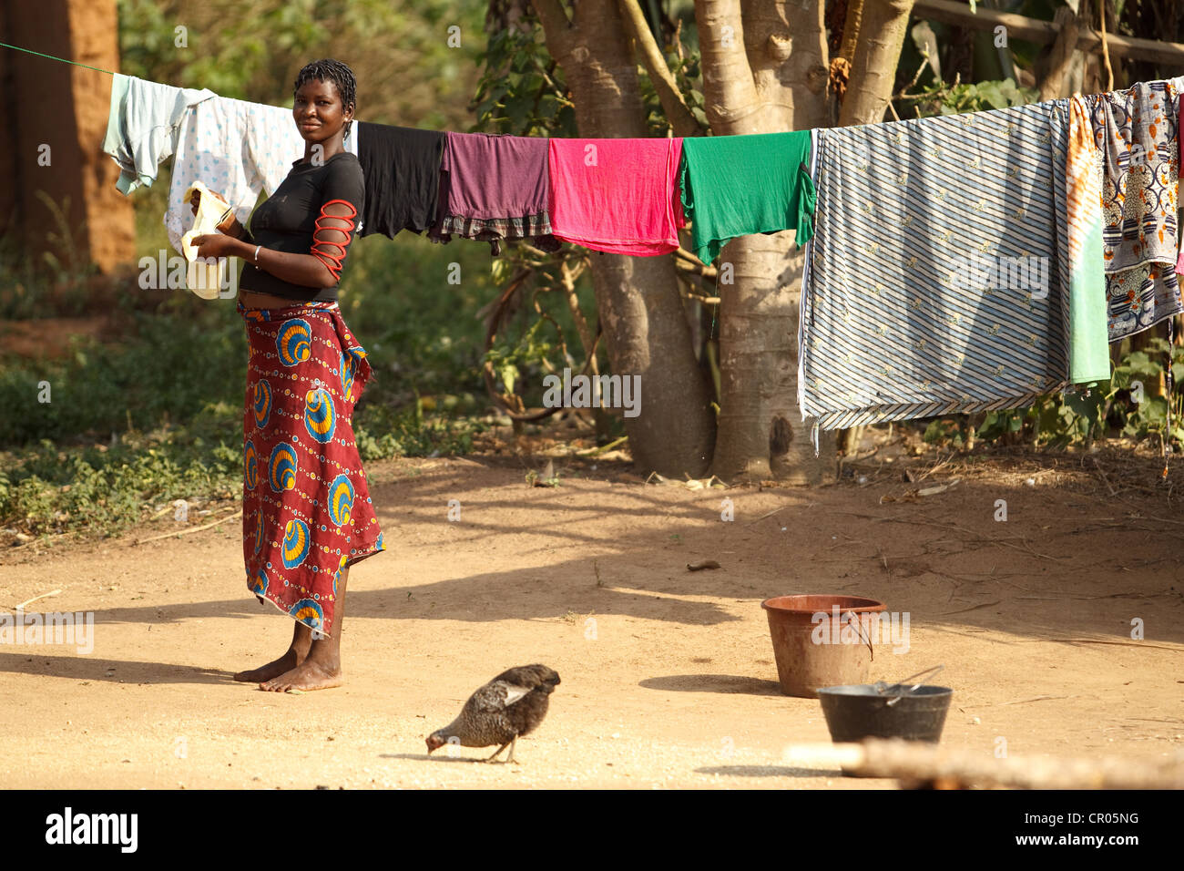 Una donna mette i vestiti fuori ad asciugare sulla linea nel villaggio di Djorbana, regione di Zanzan, Costa d'Avorio Foto Stock