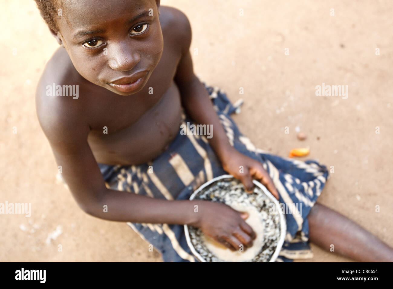 Un bambino mangia un pasto di foufou (pestate yam) e ragù vegetale nel villaggio di Djorbana, regione di Zanzan, Costa d'Avorio Foto Stock