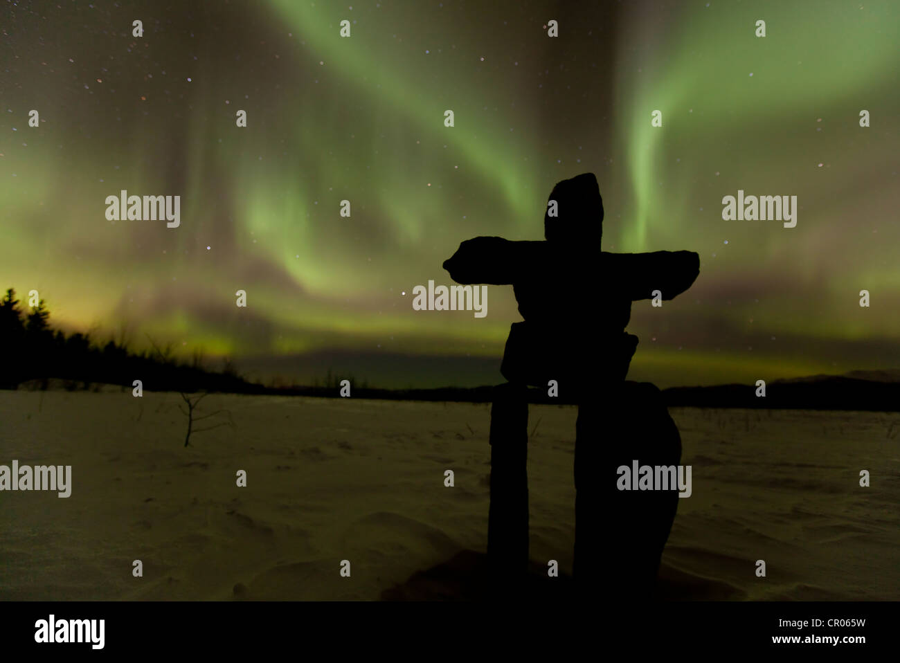 Silhouette di Inuit uomo di pietra, inukshuk oder inuksuk, pietra landmark o cairn, polare settentrionale luci, Aurora boreale, verde Foto Stock
