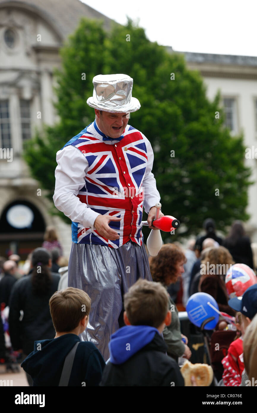 Stiltwalker vestito in Unione Jack panciotto passeggiate tra la folla in Birmingham durante il Queens celebrazioni giubilari. Foto Stock