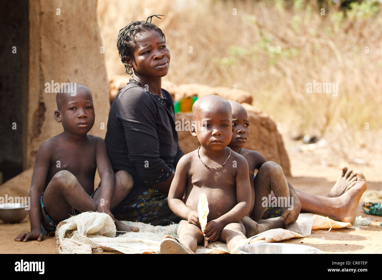 Donna e tre bambini al di fuori della loro casa nel villaggio di Kirkpadouo, regione di Zanzan, Costa d'Avorio sabato 26 novembre Foto Stock