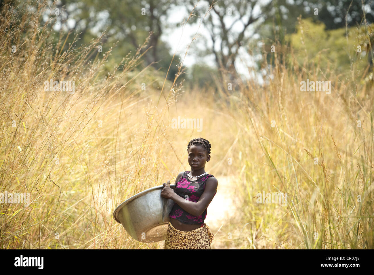 Kambou Tangba, 17, sorge lungo un percorso come ella capi al campo di lavoro nel villaggio di Kirkpadouo, regione di Zanzan Foto Stock