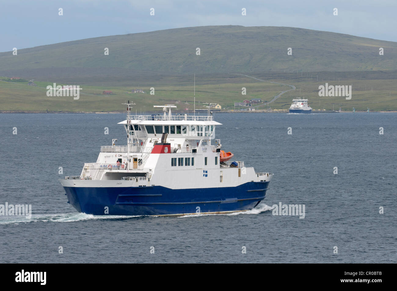 Traghetti che attraversano Yell Sound nelle isole Shetland. Traghetto 'Daggri' in primo piano. Villaggio di Ulsta e isola di Yell sfondo. Foto Stock