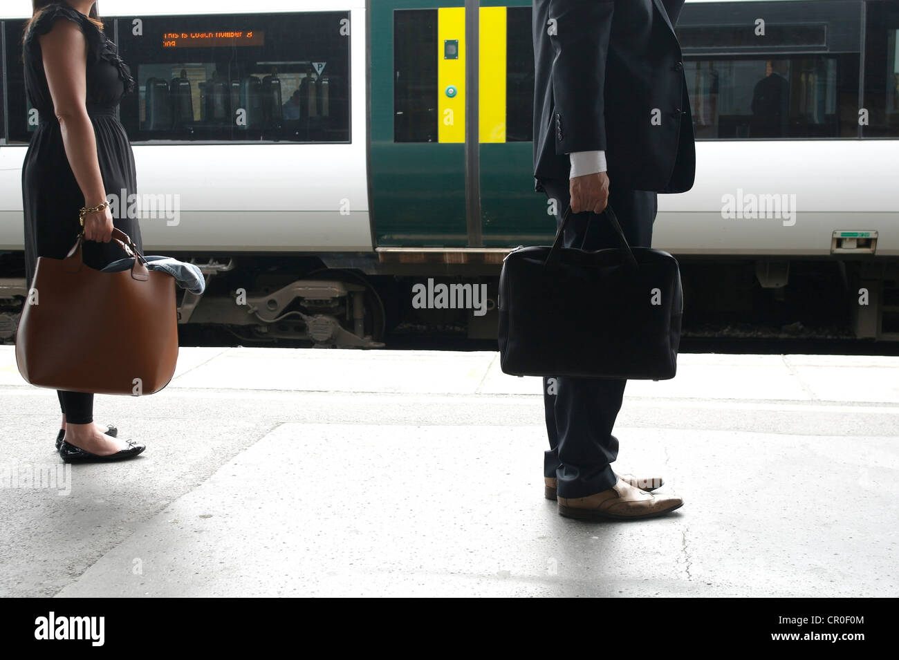 Persone con valige in attesa per i treni a Clapham Junction stazione ferroviaria Foto Stock