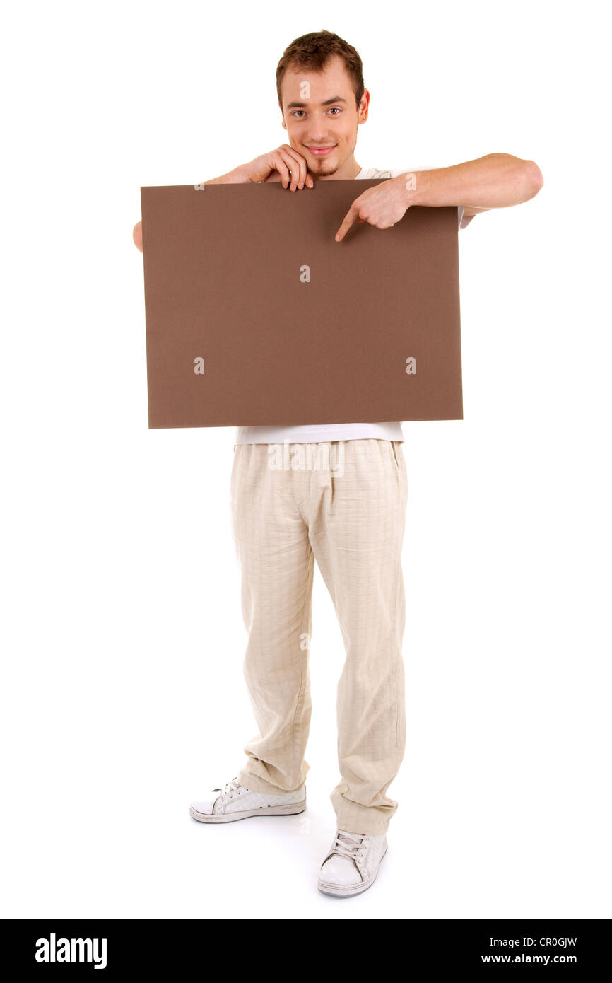 Giovane uomo in abiti casual mostra dal dito su un marrone scheda vuota per il testo Foto Stock