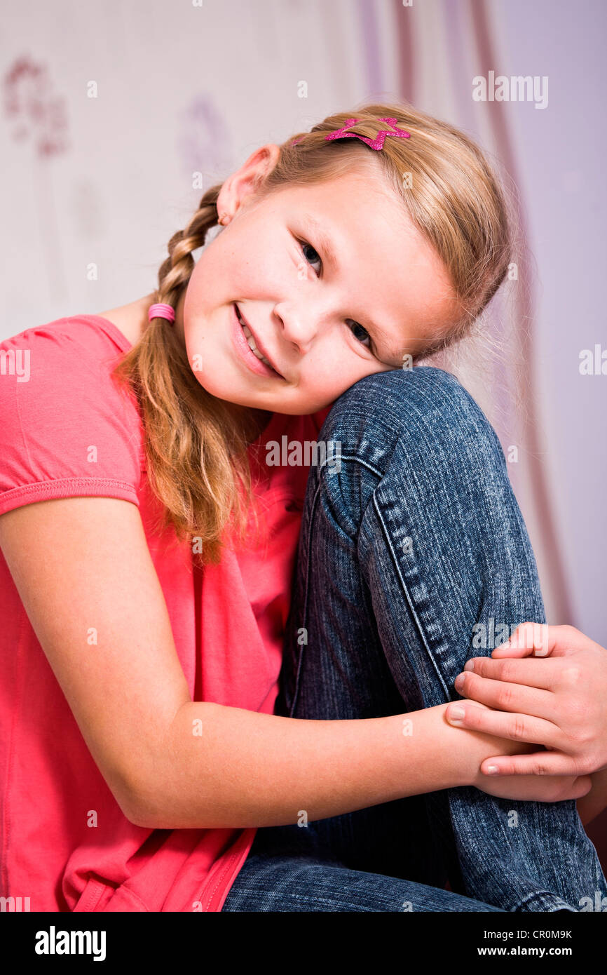 Ragazza, 11, seduta con la sua testa in appoggio sul suo ginocchio Foto Stock